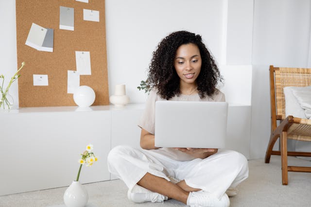 freelancer sitting on the floor holding a laptop