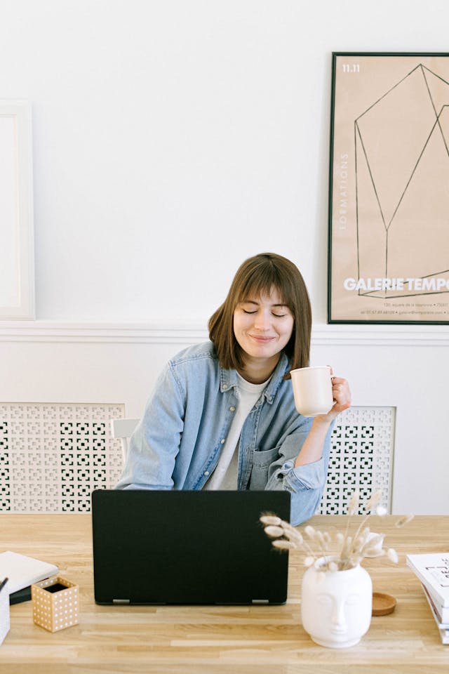 freelancer drinking coffee while writing on her laptop