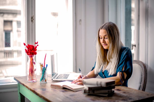 freelancer writing on table with red flower in a vase