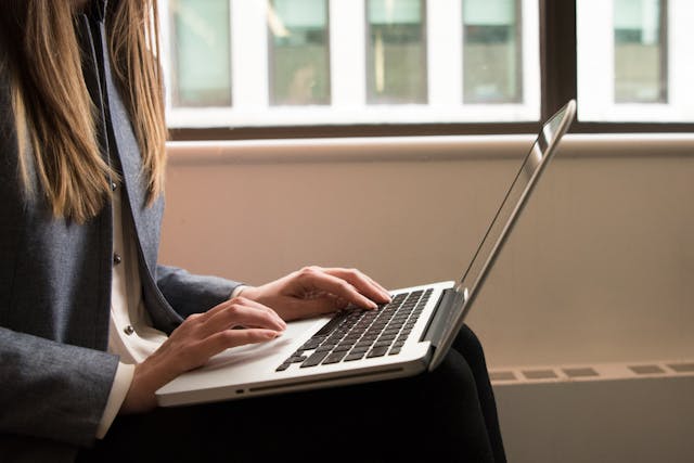 freelancer typing on her laptop near the window