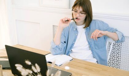 freelancer looking at her laptop with pen in her mouth