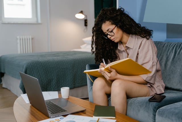 freelancer writing on her notebook while sitting on the couch