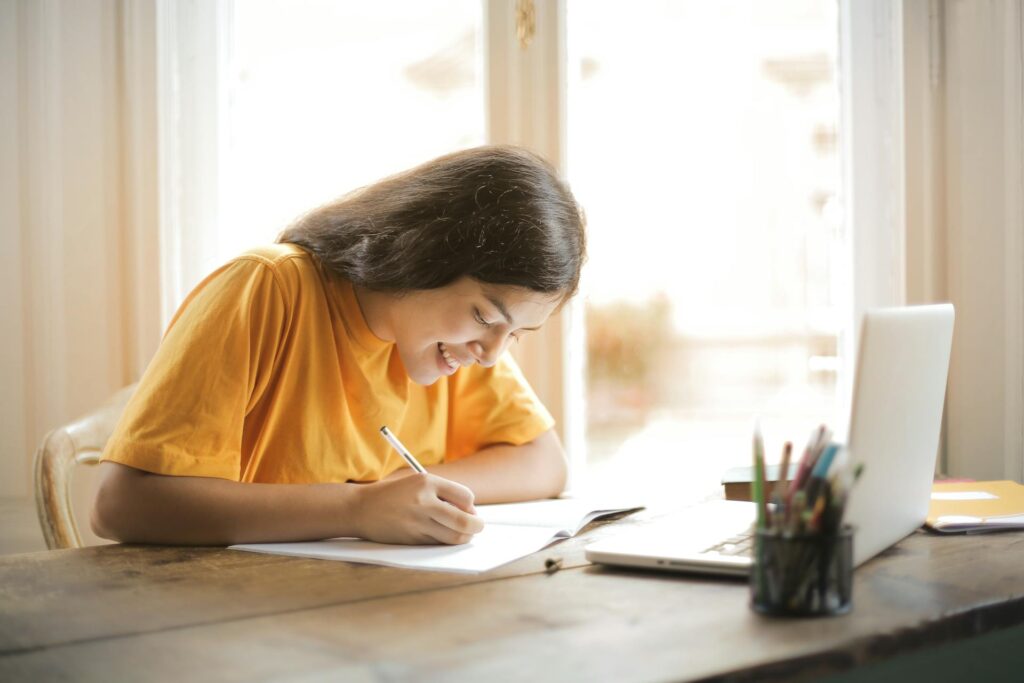 freelancer writing on her notebook wearing yellow t-shirt